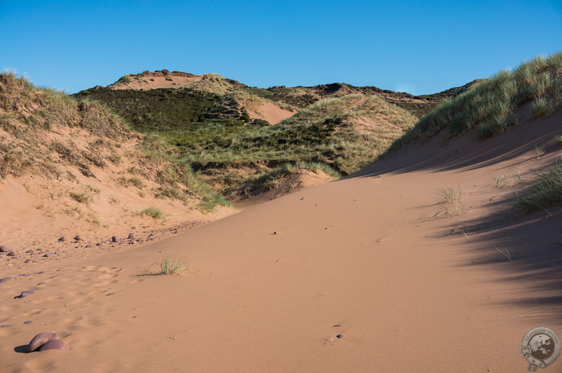 Red sands beneath green hills